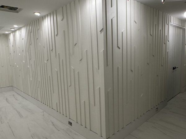 “Custom white MDF panel feature wall with vertical geometric pattern and recessed lighting — modern hallway renovation by Delghavi Design & Build in Markham.”