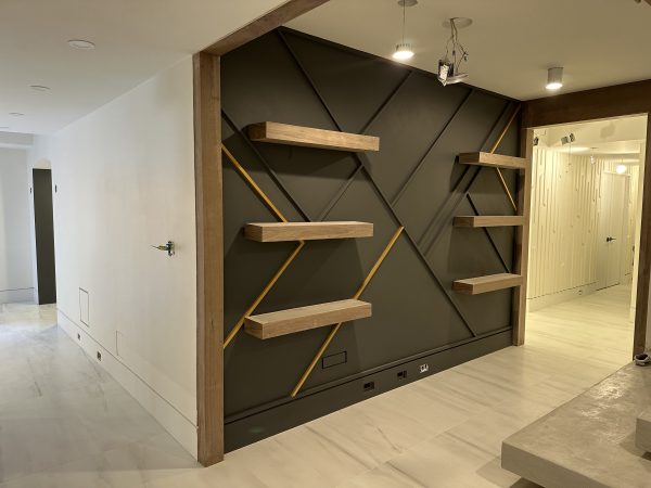 Modern hallway renovation with geometric feature wall, floating wood shelves, and accent lighting by Delghavi Design in Ontario