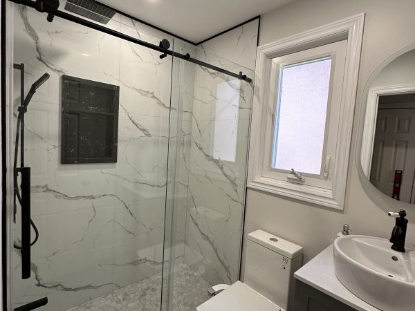 Bathroom renovation with glass shower enclosure, marble tile walls, hexagon floor tiles, and modern vanity by Delghavi Design in Vaughan