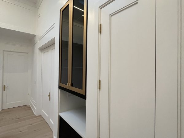 “Custom hallway cabinetry with black and gold upper doors, white quartz countertop, and detailed MDF wall paneling — luxury millwork installation by Delghavi Design & Build in Aurora.”