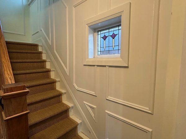 “Custom MDF wall paneling installation along staircase with decorative trim and framed stained-glass window — classic interior upgrade by Delghavi Design & Build in Etobikoce.”