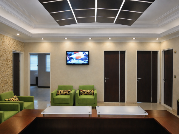 Modern clinic waiting area with custom ceiling LED panels, recessed lighting, and contemporary seating layout