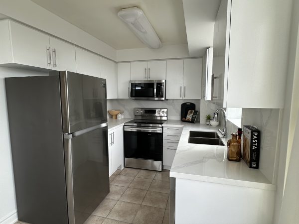 Modern white condo kitchen with quartz countertops and stainless steel appliances